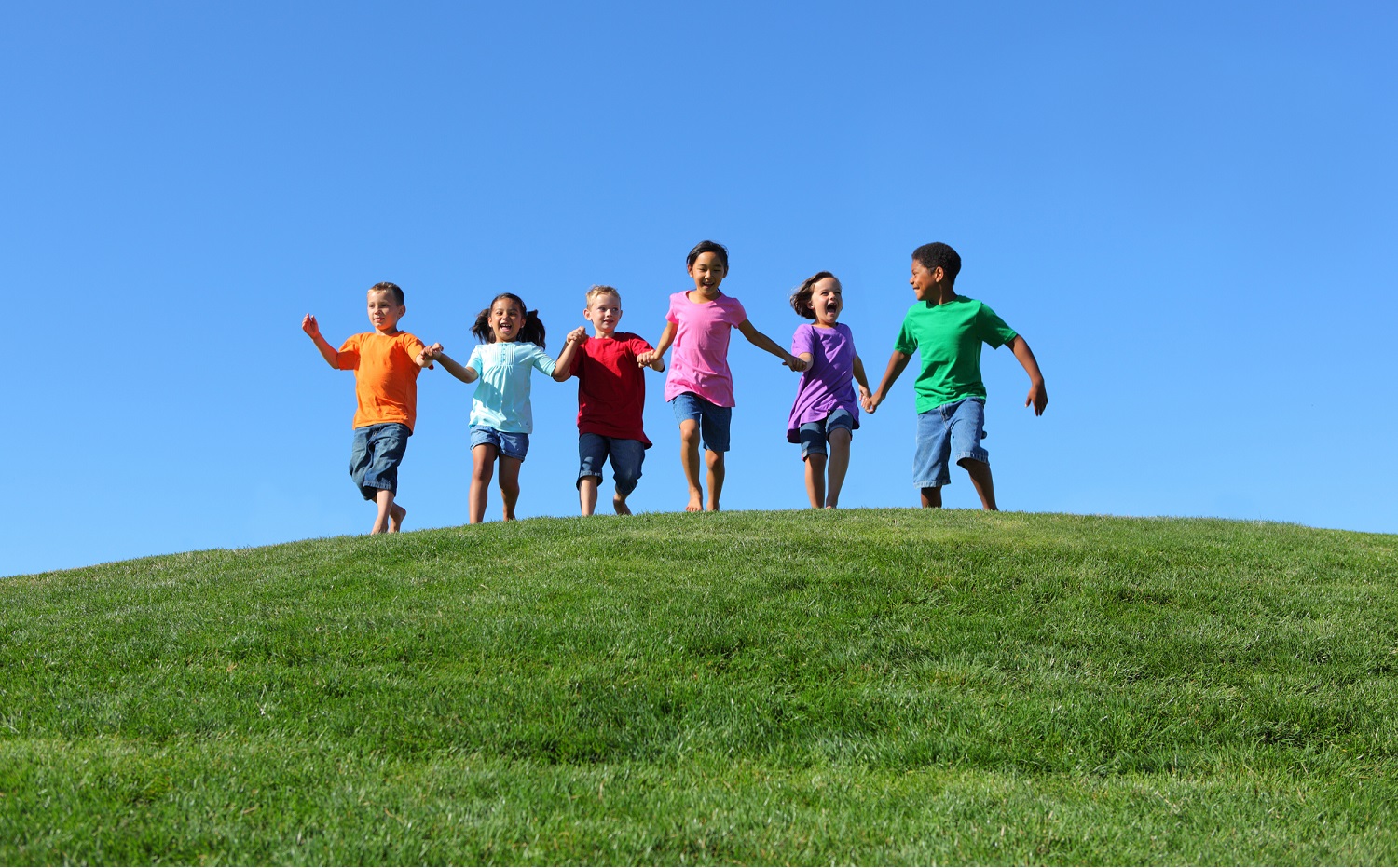 child and youth opportunity: happy children running over grassy hilltop towards camera