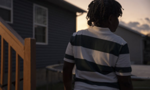 11-year old juvenile arrest for making threat in Tennessee: view of young black child from behind in horizontal striped shirt at dusk