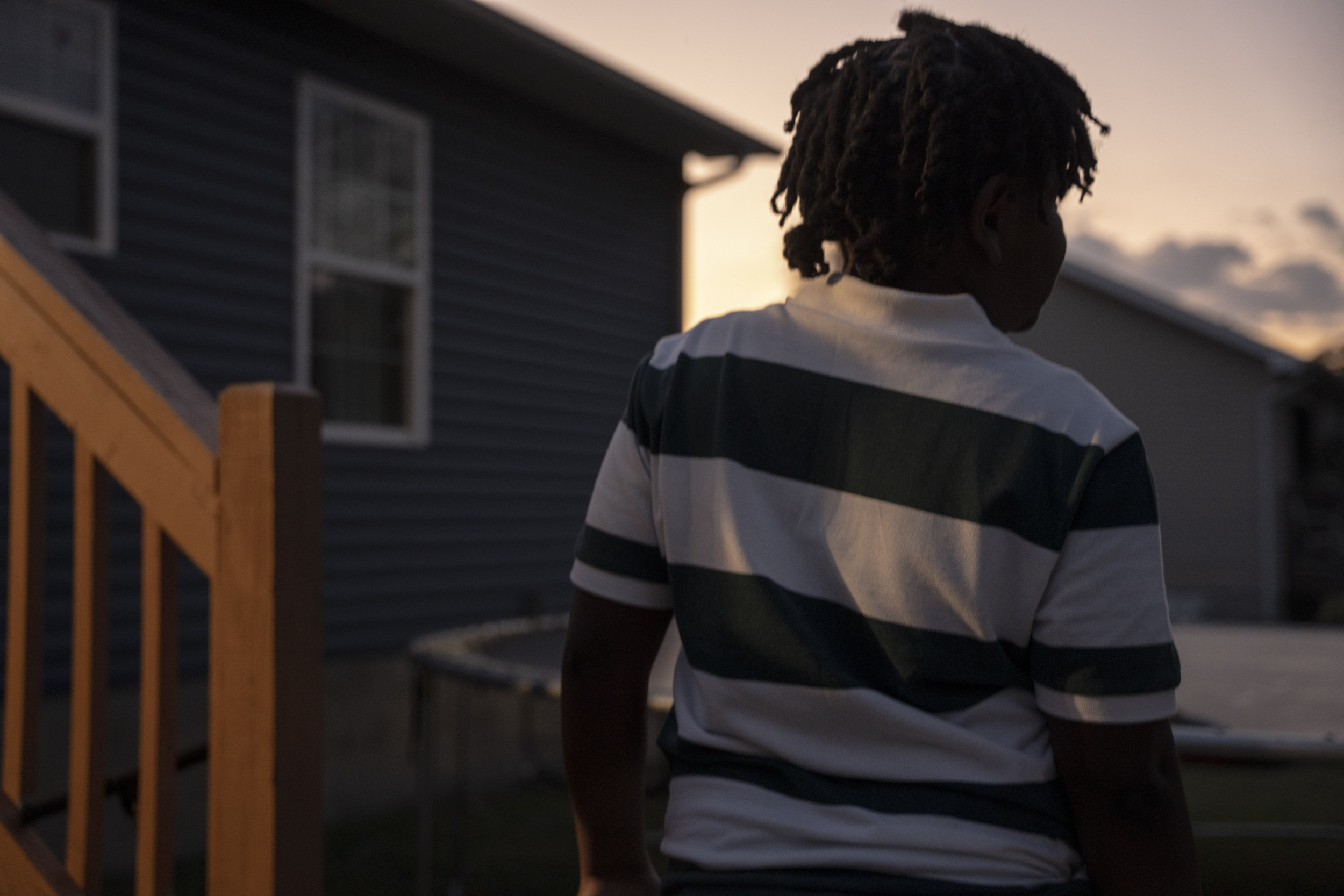11-year old juvenile arrest for making threat in Tennessee: view of young black child from behind in horizontal striped shirt at dusk