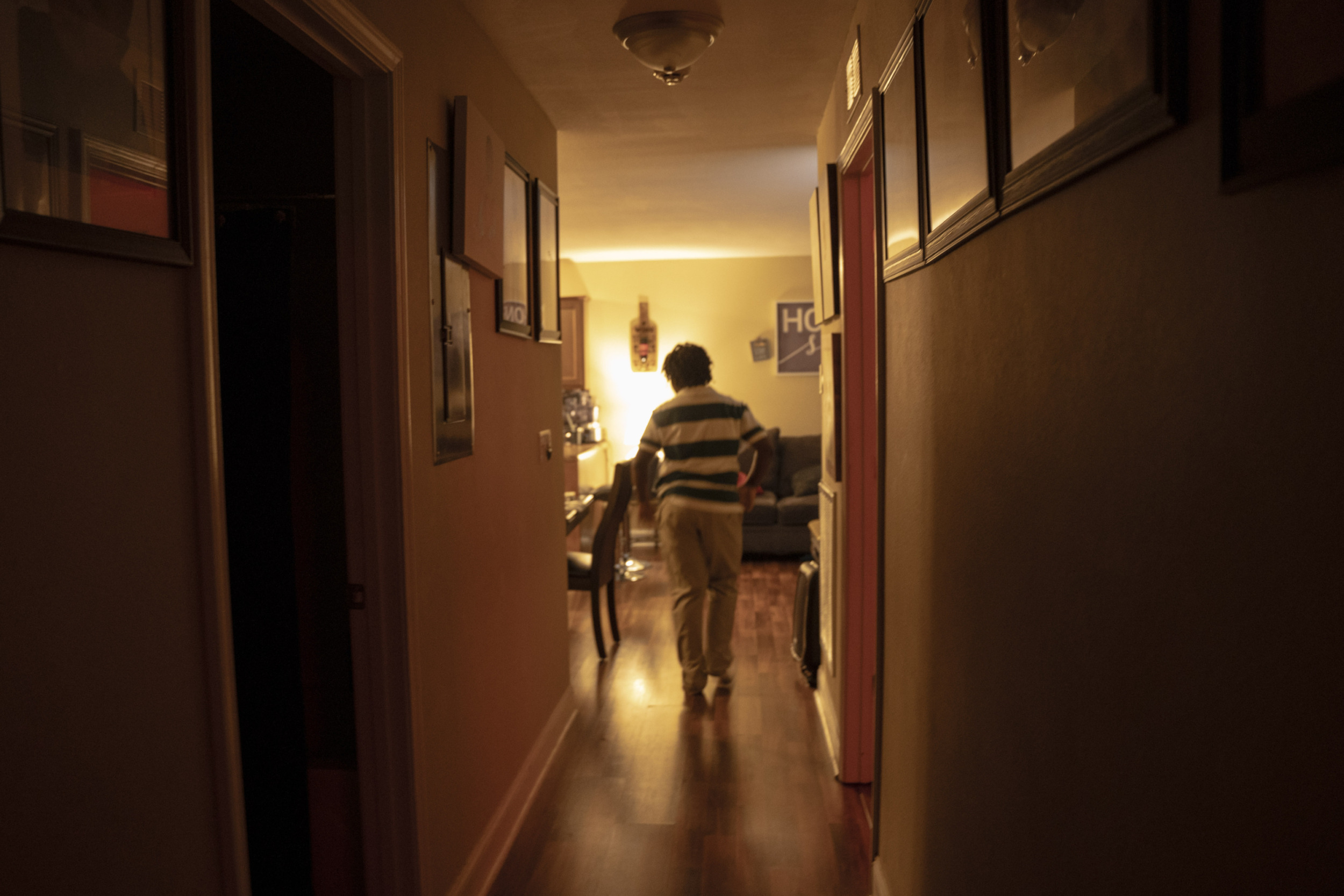 11-year old arrested for making threat in Tennessee: view of young black child form behind in hallway of home horizontal striped shirt