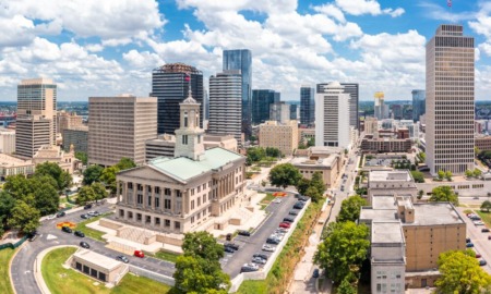 Free college tuition: Long view of traditional off-white multi-story building surrounded by a parking lot, other city buildings and skyscrapers.